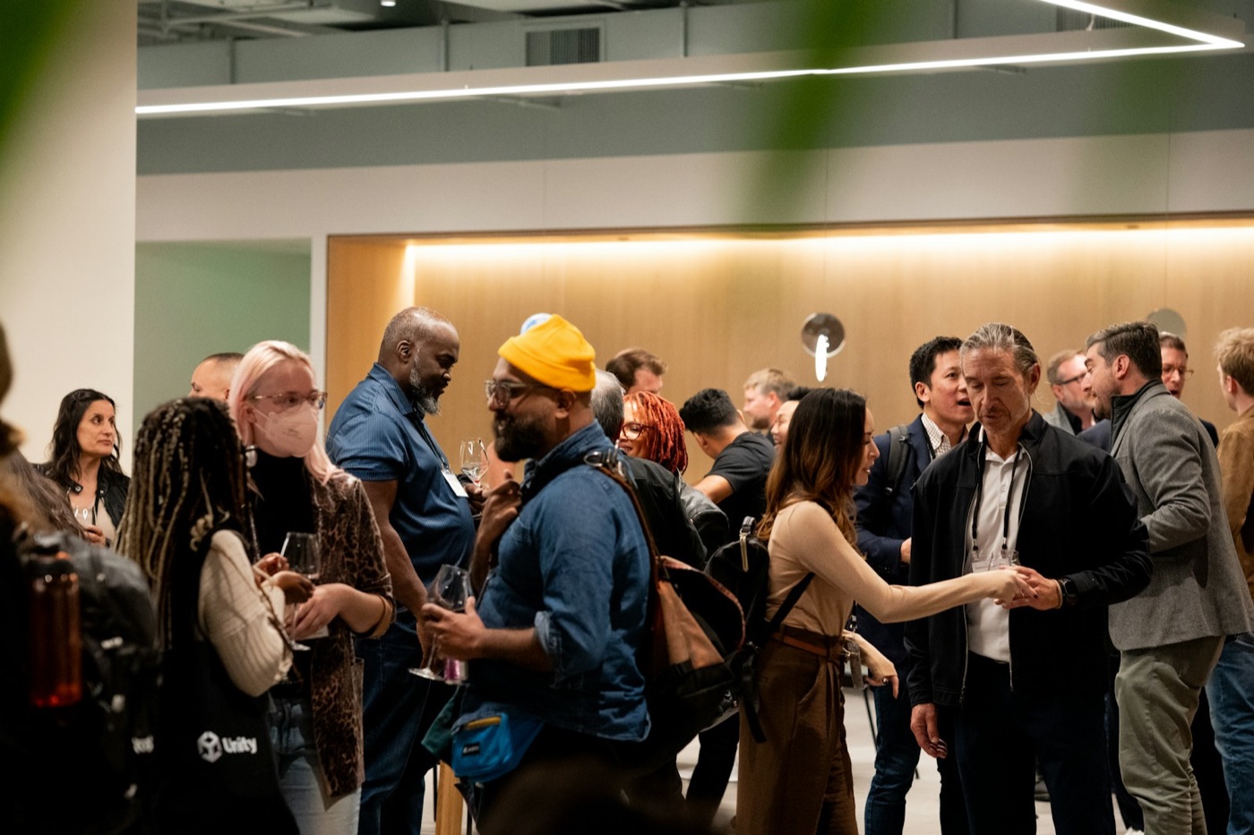 A busy evening networking event: people talking in small groups, drinks in hand
